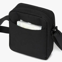 Black crossbody bag with a pocket open, showing a white bag inside on a white background.