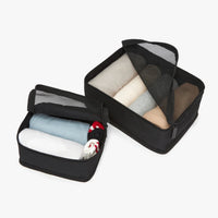 Black packing cubes with folded clothes on a white background